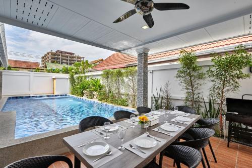 南芭堤雅Gala Villa Pattaya的一间带桌子和游泳池的用餐室
