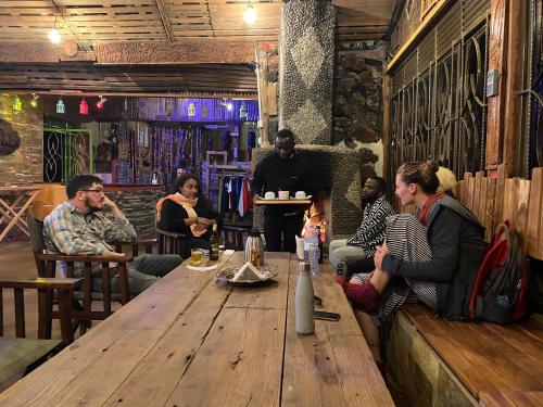 KisoroMondi Lodge Kisoro的一群人坐在酒吧的木桌旁