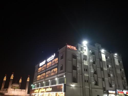 尼兹瓦Aryaf Nizwa Hotel Apartments的一家晚上在上面标有标志的酒店