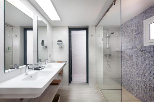 奇克拉纳－德拉弗龙特拉Hotel Riu Chiclana - All Inclusive的一间带两个盥洗盆和淋浴的浴室