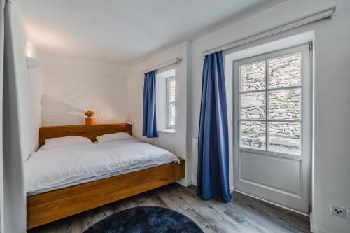 杜伦斯坦Smile Apartments zum Goldenen Strauß的一间卧室配有一张带蓝色窗帘的床和一扇窗户