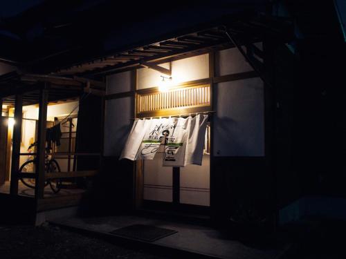 富士市Kinoya Hostel的夜间门上带有标志的建筑
