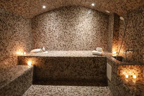 布里夫拉盖亚尔德Hôtel SPA Le Miel des Muses的浴室设有大浴缸,内配蜡烛