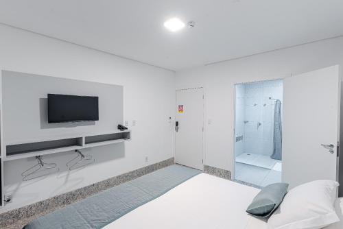 蓬塔波朗Prime Hotel Ponta Porã的白色的浴室设有电视和淋浴。