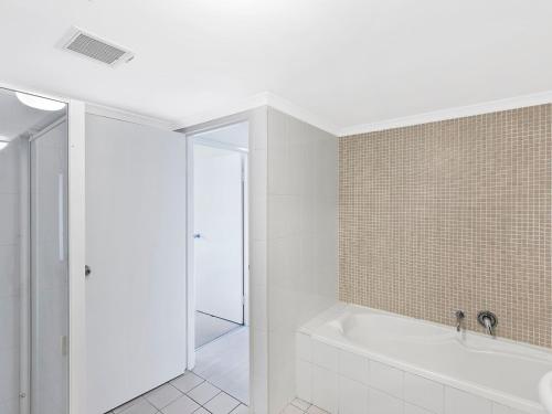 安特兰斯双岸67公寓的白色的浴室设有浴缸和淋浴。