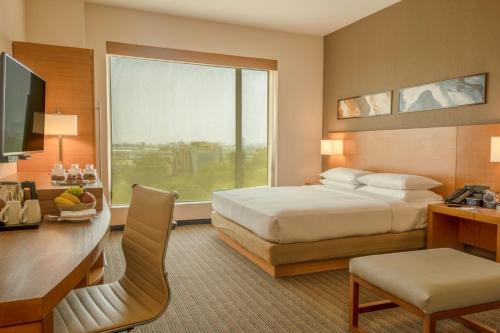 古尔冈Hyatt Place Gurgaon Udyog Vihar的配有一张床、一张书桌和一扇窗户的酒店客房
