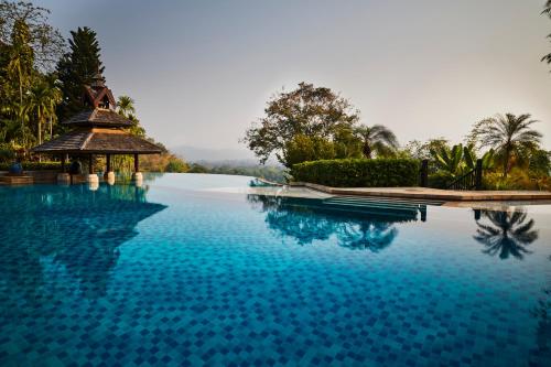 金三角Anantara Golden Triangle Elephant Camp & Resort的一个带凉亭和蓝色海水的游泳池