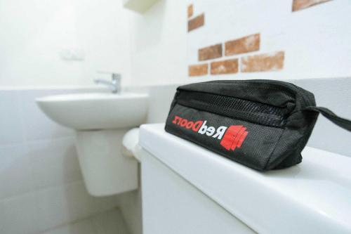 TanjungkarangRedDoorz near Lampung Walk 2的坐在浴室柜台上的黑袋