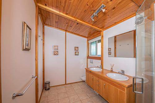 布伦海姆Mountainview Villa Luxury Lodge & Glamping的一间带两个盥洗盆和木制天花板的浴室