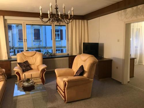 莱布尼茨Charmante Stadtwohnung im Zentrum von Leibnitz的客厅配有两把椅子和电视