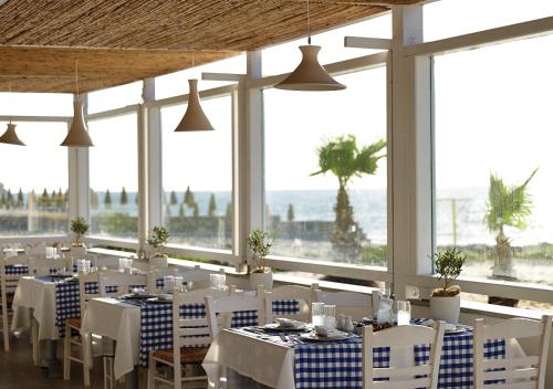 马斯蒂查里Atlantica Marmari Palace的餐厅设有白色的桌子和白色的椅子及窗户。