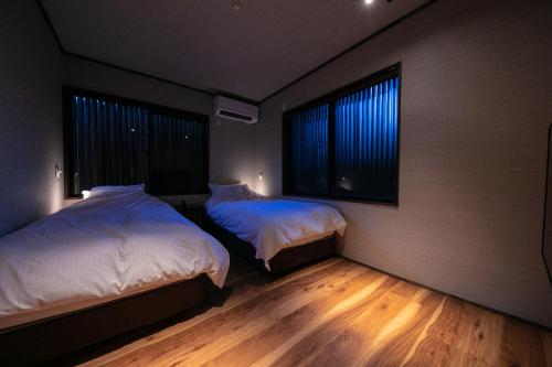 由布市汤布院风之森旅馆的一间卧室设有两张床和两个窗户。