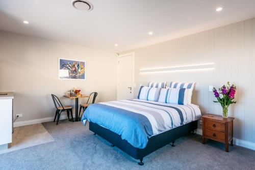 OmihaThe Apartment - Sea Views at Te Whau Point by Waiheke Unlimited的一间卧室配有一张床和一张花瓶桌子