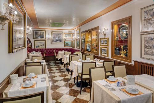 威尼斯阿琵亚韦酒店的餐厅设有桌椅,墙上挂有绘画作品