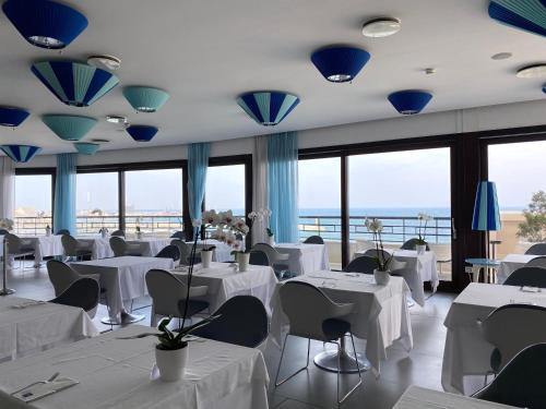 巴里JR Hotels Bari Grande Albergo delle Nazioni的餐厅设有白色的桌椅和窗户。