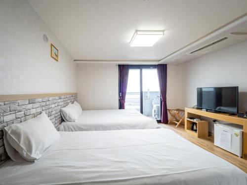 西归浦市济州摹瑟普酒店的酒店客房设有两张床和一台平面电视。