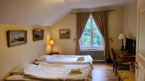 科尔巴克斯科尔巴克斯加斯特吉瓦尔加德酒店的一间卧室设有两张床、一张桌子和一个窗口。
