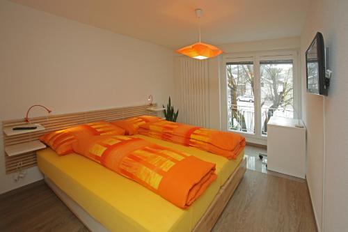 迪格滕兰德格斯霍夫赫尔森酒店的一间卧室配有带橙色枕头的大型黄色床