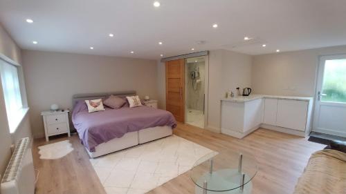 克努斯福德The Garden Room, 1 Heath Cottage的一间卧室配有一张紫色床单的床和一间厨房