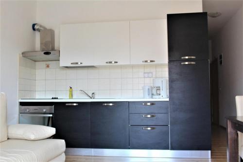 普利莫顿Apartment Jure的厨房配有白色橱柜和黑色冰箱。