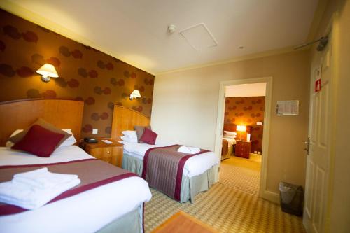 卡莱尔Crown & Mitre Hotel的一间酒店客房,设有两张床和走廊