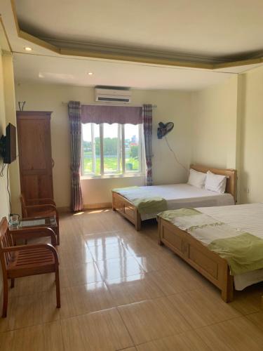 河内Nhà nghỉ Diễm Quỳnh Nội Bài的一间卧室设有两张床、一把椅子和一个窗户。