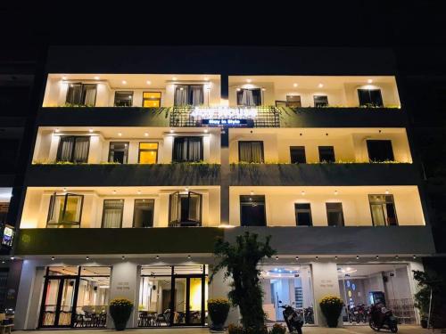 绥和市Joy Hotel Phú Yên的夜间有照明的建筑,摩托车停在前面