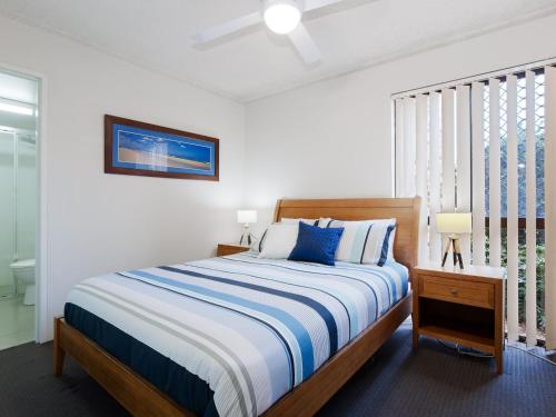 尼尔森湾Bay Parklands 57 ground floor unit with pool tennis court and aircon的一间卧室配有一张带蓝白色床单的大床