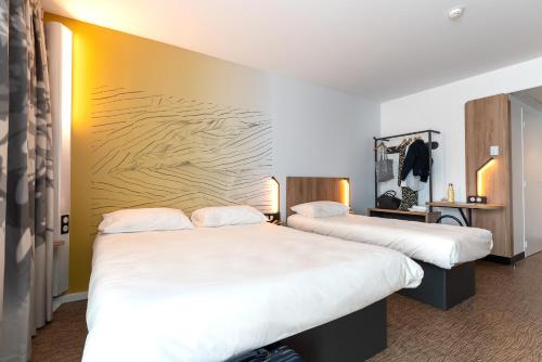 普瓦捷B&B HOTEL Poitiers Aéroport的酒店客房,配有两张带白色床单的床
