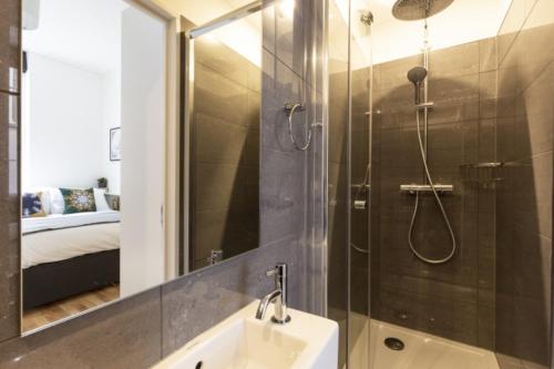伦敦Bloomsbury By Viridian Apartments的带淋浴、盥洗盆和镜子的浴室