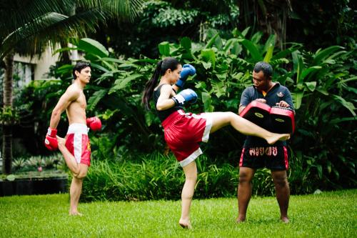 迈考海滩Anantara Vacation Club Mai Khao Phuket的一群三人站在草地上,手套拳击