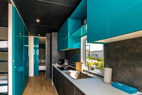 梅杜林Arena Grand Kazela Camping Homes的厨房配有蓝色橱柜和水槽