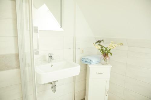 滕宁Ferienwohnungen Zum Goldenen Anker的白色的浴室设有水槽和花瓶