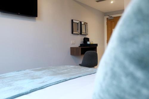 伦敦CG Kensington的一间卧室配有一张床、一把椅子和电视