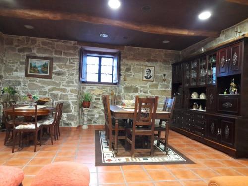 卢戈Albergue Rectoral de Romean的一间设有桌椅和石墙的用餐室