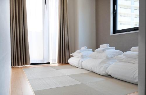 东京The Light Inn - Vacation STAY 94696的窗户客房内的一张带白色枕头的床