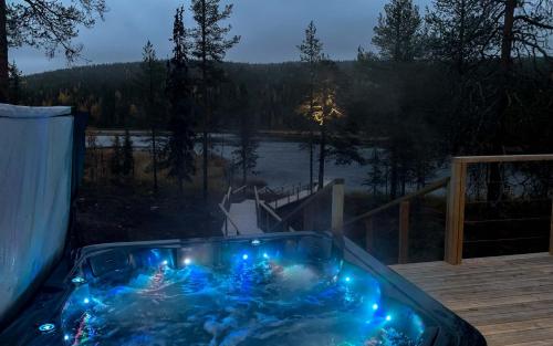 阿卡斯洛姆波罗Arctic Skylight Lodge的甲板上配有蓝色灯光的按摩浴缸