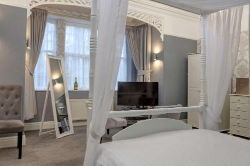 贝里贝斯特韦斯特宝号特酒店加休闲俱乐部的卧室配有白色的天蓬床和电视。