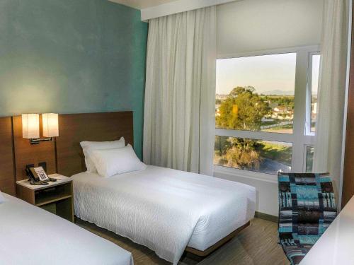 圣若泽杜斯皮尼艾斯ibis Styles Curitiba Aeroporto的酒店客房设有两张床和窗户。