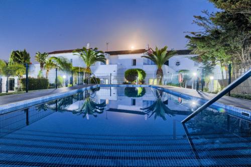 科尼尔-德拉弗龙特拉弗拉门戈海滩科尼尔别墅酒店的一座游泳池,在晚上在建筑物前