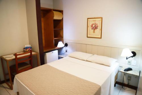 贝洛奥里藏特BH宫殿酒店的小房间设有一张床、一张桌子和一张书桌