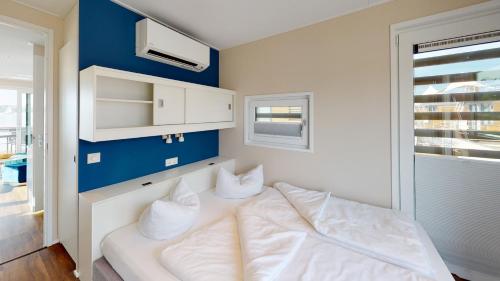 RamsbergFloating Village Brombachsee的一间卧室配有一张带白色床单和蓝色墙壁的床。