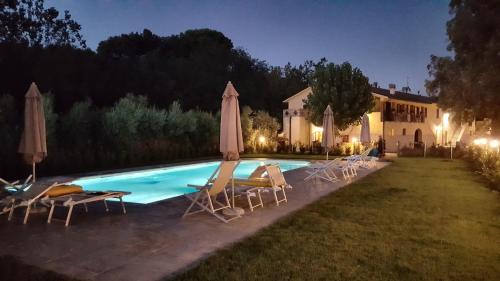 里帕尔贝拉Punta dei Lecci的房屋前的带椅子和遮阳伞的游泳池