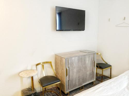 东京The Barn Tokyo的卧室配有两把椅子和墙上的电视。