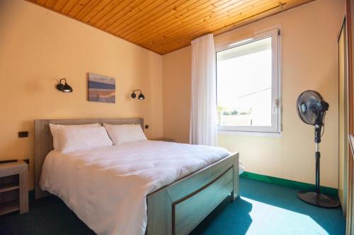 滨海勒韦尔东Contact HOTEL LES TERRASSES的一间卧室配有一张带窗户的床和风扇