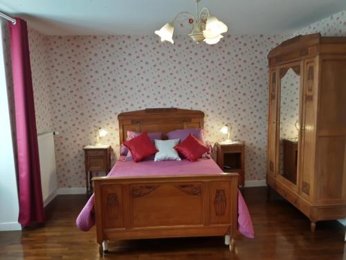圣梅尔埃格利斯Chambres d'Hôtes et Table d'Hôtes- Valentine 44的一间卧室配有一张带红色枕头的木床。