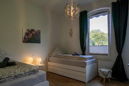 巴德茨维什安HausAltenkamp的一间卧室设有两张床、一个窗户和一个吊灯。