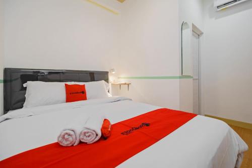 BuaranRedDoorz @ Taman Royal Tangerang的卧室配有一张带红色毯子的白色床