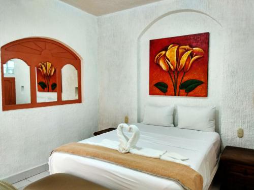 阿卡普尔科D'Cesar Hotel Acapulco的卧室配有一张床,墙上挂有绘画作品