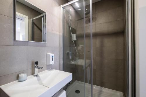 蓬塔德尔加达Magma Hostel的一间带水槽和玻璃淋浴的浴室